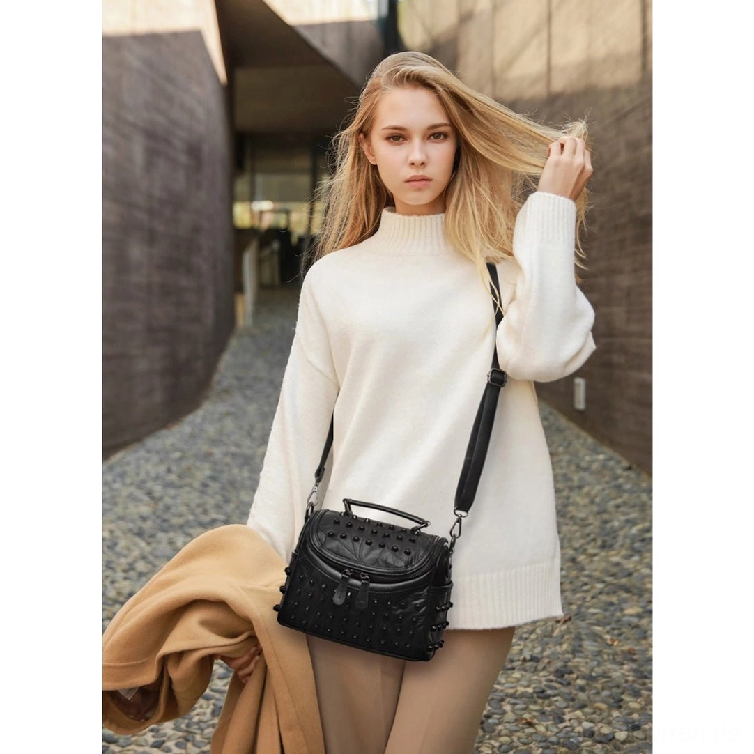 Schwarze Leder-Messenger Bag mit Metallnieten getragen als Crossbody, demonstriert authentische Alternative Fashion Stil und Gothic Subkultur Ästhetik