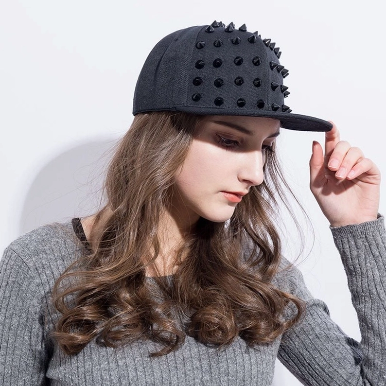 Modell passt die All-Black Spike Gothic Snapback Kappe an, Seitenansicht drei-viertel mit langen Haaren und Druckknopf-Verschluss