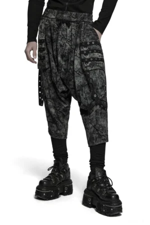 Schwarze Tie-Dye Gothic Haremshose Vorderansicht mit Drop-Crotch-Silhouette und Ösen-Cargo-Taschen, getragen von männlichem Model mit Platform-Boots