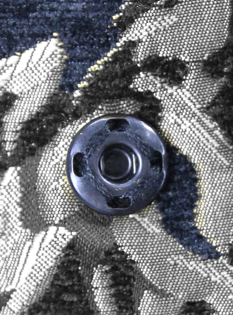 Schwarzer silberner Damast Gothic-Mantel ärmellos – Rundes dunkles Metallknopf-Detail auf silbernem Damast-Jacquard Textil-Nahaufnahme, Knopf auf Stoffoberfläche montiert
