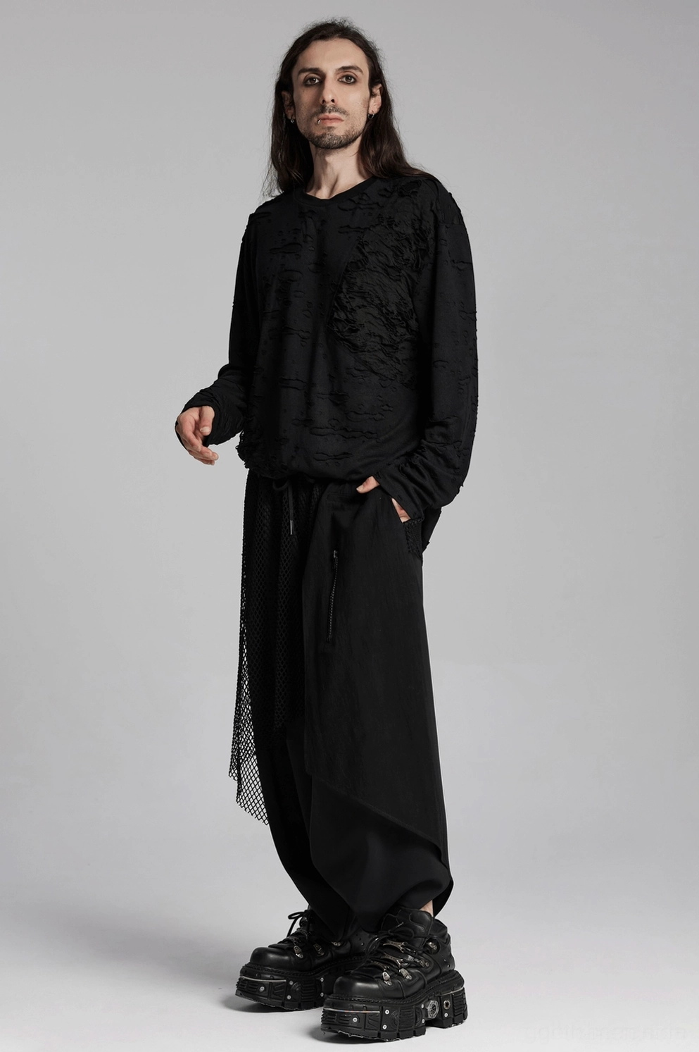 Männliches Model trägt schwarzen zerrissenen Gothic Strickpulli mit langem Haar in Alternative Fashion Setting-Szene
