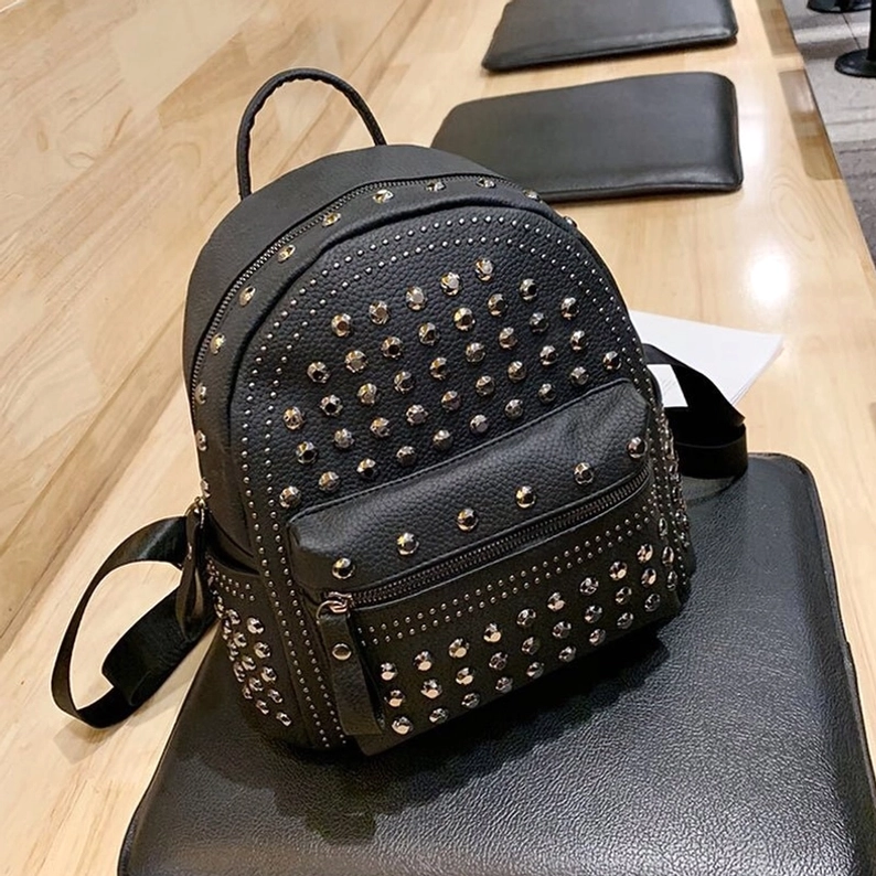 Schwarzer Gothic Nieten-Rucksack Dreiviertelansicht vorne, zeigt komplette Nieten-Platzierung, Frontreißverschluss und polierte Metalldetails