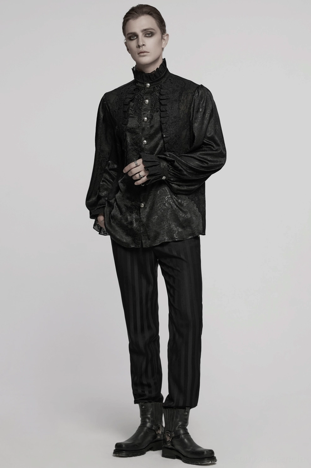 Männliches Model im schwarzen viktorianischen Gothic-Hemd mit dramatischen rüschigen Details, theatralischem Stil und aristocratischer Gothic-Ästhetik vor dunklem Hintergrund