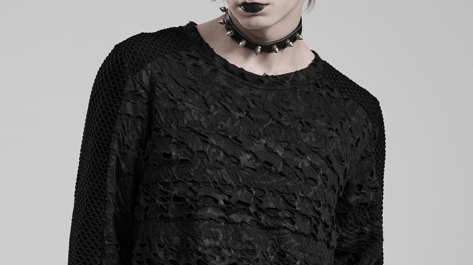 Nahaufnahme schwarzes gothisches Mesh-Sweatshirt Vorderansicht mit Spike-Choker-Styling und Distressed-Stoffdetail auf männlichem Modell