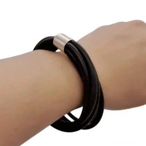 Schwarzes Silikon-Gummi Gothic Armband mit rose-gold Metallverschluss, Seitenaufnahme am weiblichen Handgelenk mit mehrschichtigen Gummibändern und geometrischem Industrial-Design