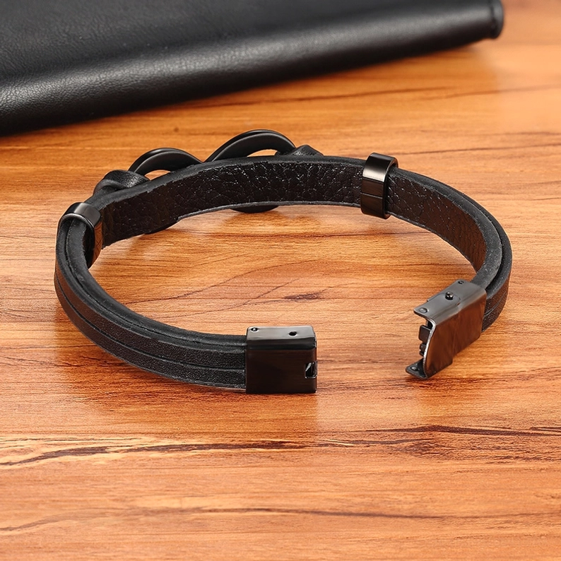 Schwarzes Infinity-Lederarmband Seite Draufsicht auf Holzoberfläche zeigt öffnende Metallverschluss Struktur und Mechanik