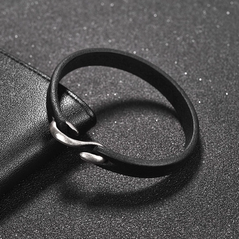 Nahaufnahme von oben: schwarzes Lederarmband mit detailliertem Bootshaken-Verschluss, matte Oberfläche, Lederkörnung sichtbar