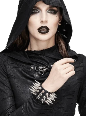 Gotisches Leder-Armband mit silbernen Spikes an weiblichem Modell in dunklem Gothic-Outfit mit Kapuze im Studio-Setting – detaillierte Nahaufnahme der Spike-Struktur