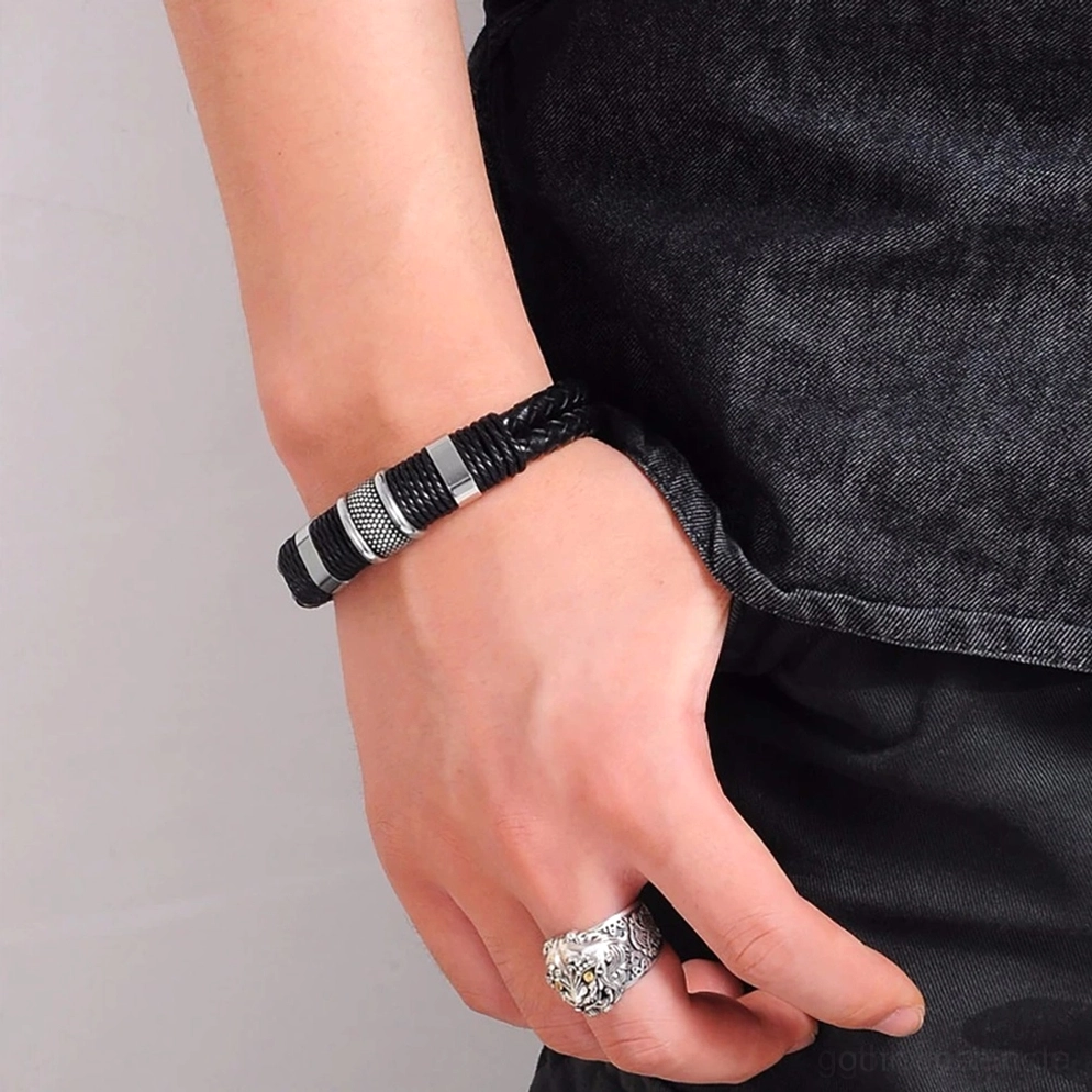 Tragefoto des schwarzen Leder-Gothic-Toggle-Armbands am männlichen Handgelenk mit silbernen Ringen, zeigt realistisches Styling in alltäglichem Outfit