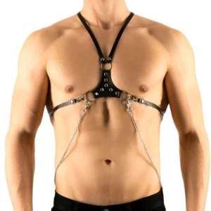 Schwarzes PU-Leder-Harness mit versilberten Nieten und hängenden Kettenelementen, Vorderansicht auf männlichem Model – Gothic Chest Harness mit D-Ringen und strukturiertem Brustpanel
