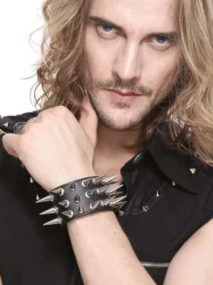Männliches Goth-Modell mit langen Haaren präsentiert doppelreihiges schwarzes Leder-Spike-Armband – Nahaufnahme zeigt silberne Kegel-Spikes und Verarbeitung