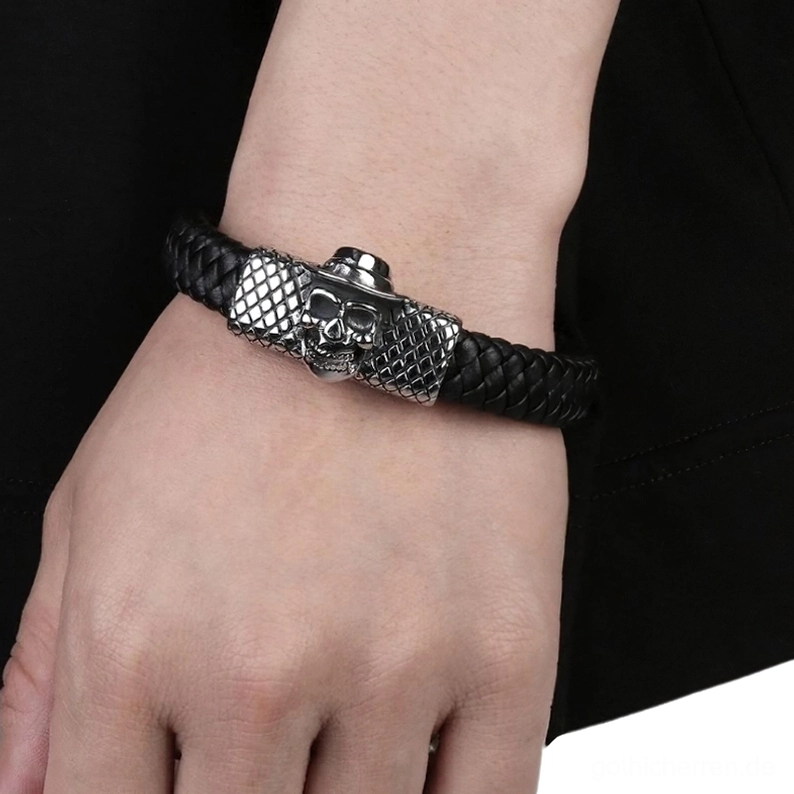 Schwarzes Leder Schädel Armband getragen am männlichen Handgelenk, nahaufnahme-frontalansicht vor dunklem Hintergrund, punk-stil silberner charm mit magnetverschluss