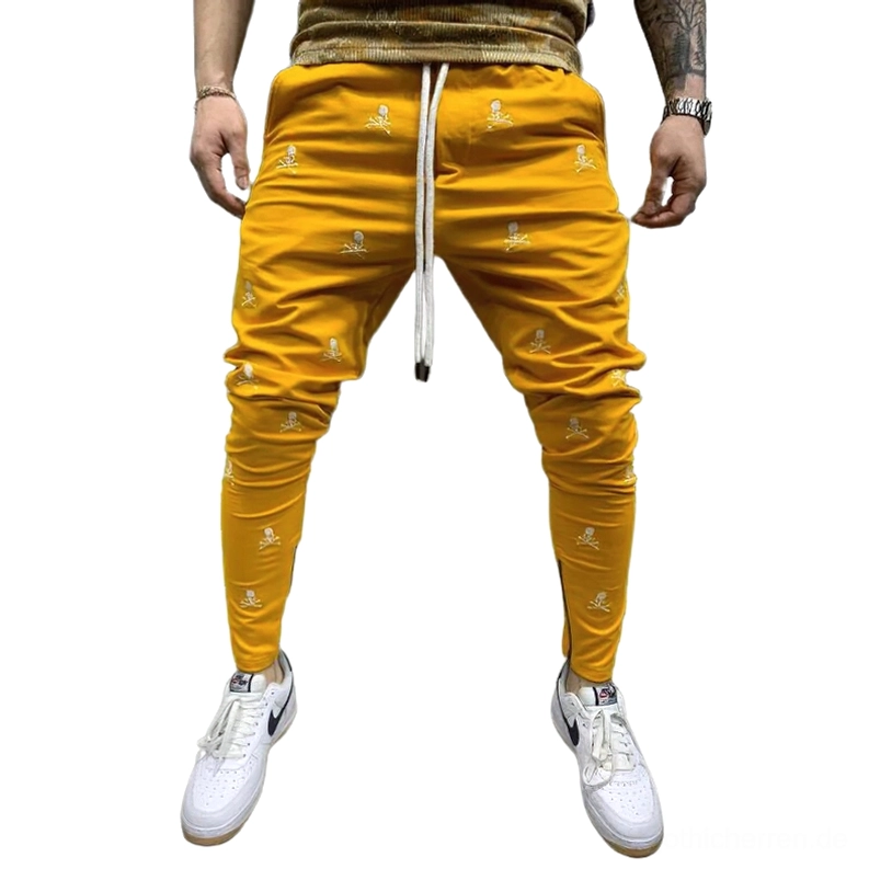 Senf-Gelb Totenkopf-bedruckte Gothic Lace-Up Röhrenhose für Herren, kühne alternative Fashion-Trousers mit Senf-gelber Basis, weißem Skull-Print, Schnürweste und seitliche Knöchel-Reißverschlüsse, Gothic Slim-Fit Design