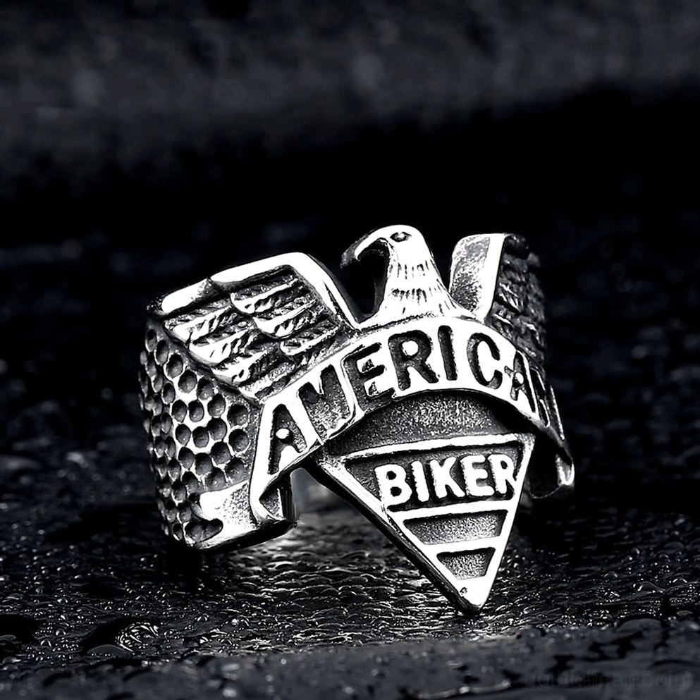 Silberfarbener Gothic Adler Biker Ring in Schrägansicht auf dunklem Wassertropfen Hintergrund - zeigt gehämmerte Bandstruktur und Flügeldetails