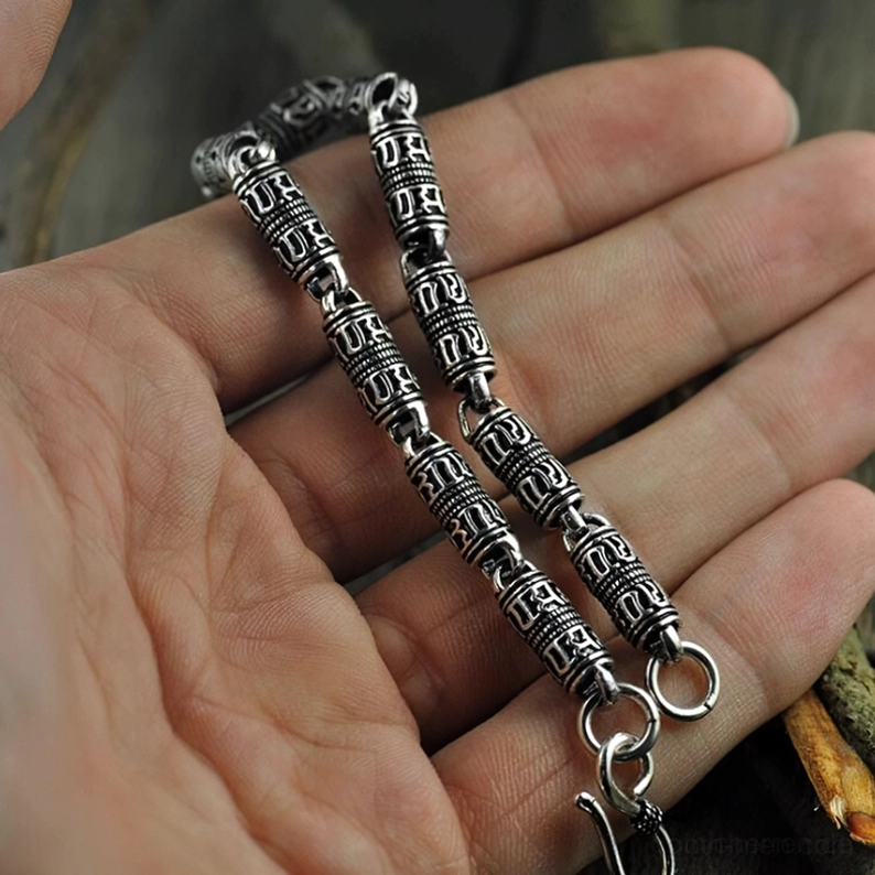 925er Sterling Silber Armband in Hand gehalten, augenhöhen Nahaufnahme zeigt kunstvolle gravierte Muster auf zylindrischen Perlen, Hakenverschluss, natürliches Licht, okkulte Symbole