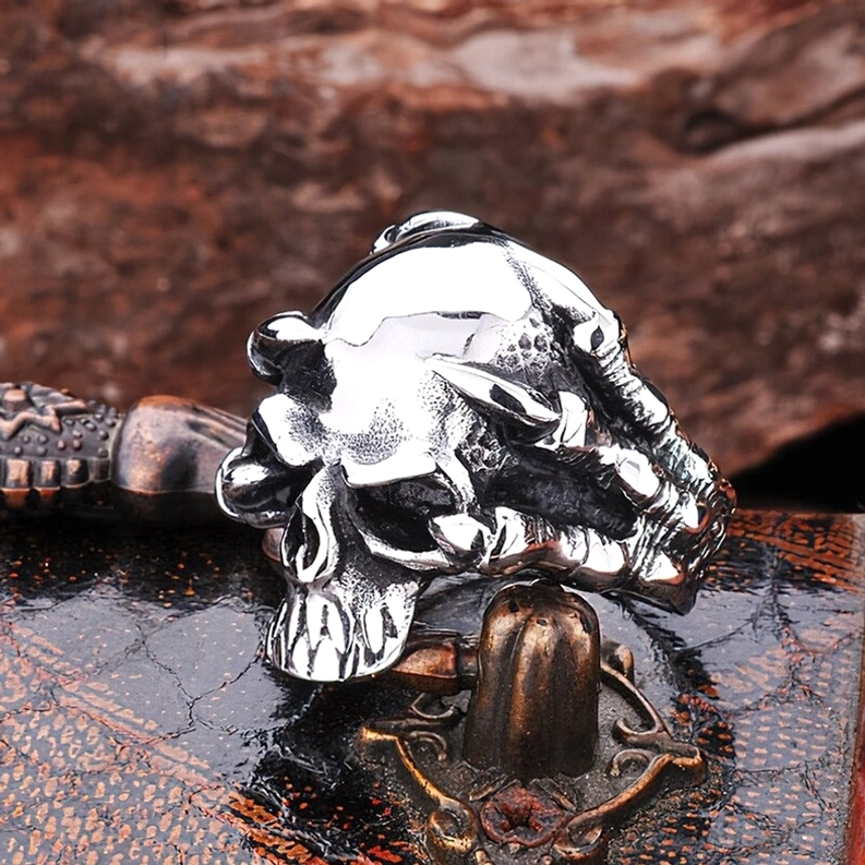 Silberner gotischer Totenkopf-Krallen-Ring ruhend auf Vintage-Metallhardware und Leder, gestylt mit Antik-Dekoration zeigt Dark-Aesthetic-Lifestyle-Kontext und Biker-Ästhetik