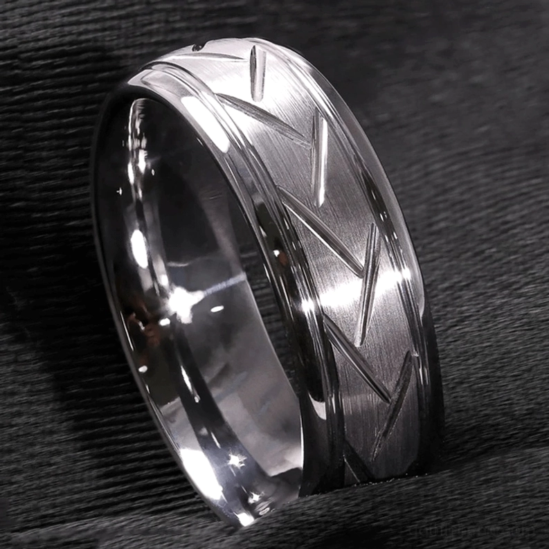 Silberner Chevron Zickzack Ring mit mattiertem Finish auf dunklem Hintergrund, glänzende Metalloberfläche, geometrische Zickzack-Struktur, detailliertes Muster, Lichtreflexion