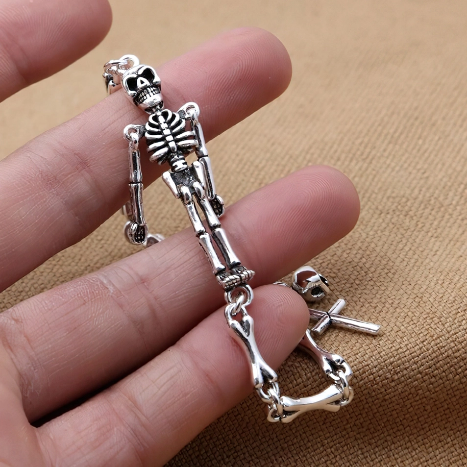 Nahaufnahme Sterling Silber Skelett Armband am Handgelenk getragen, detaillierte Ansicht des Schädel-Anhängers, Toggle-Schließe und gotische Knochenketten-Textur