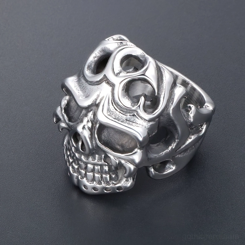 Drei-Viertel-Seitenprofile des Edelstahl Totenkopfring mit Tribal-Hohlschnitzereien auf dunklem grauem Hintergrund, zeigt realistische Schädelstruktur und Gothic-Details
