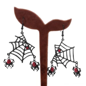 Schwarze Spinnen-Hänger Ohrringe auf Schmuck-Ständer, Frontansicht zeigt filigrane Spinnennetz-Struktur, rote Rhinestones und mattschwarz Finish