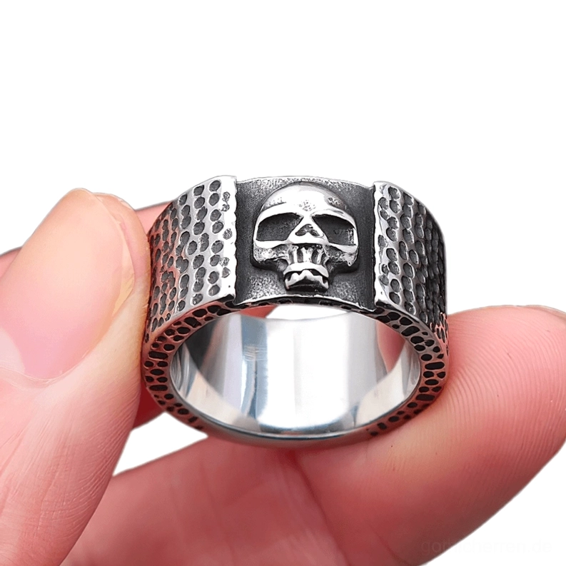 Stainless steel skull biker ring held on human fingers showing vintage silver-black tone polished inner band and side profile detail