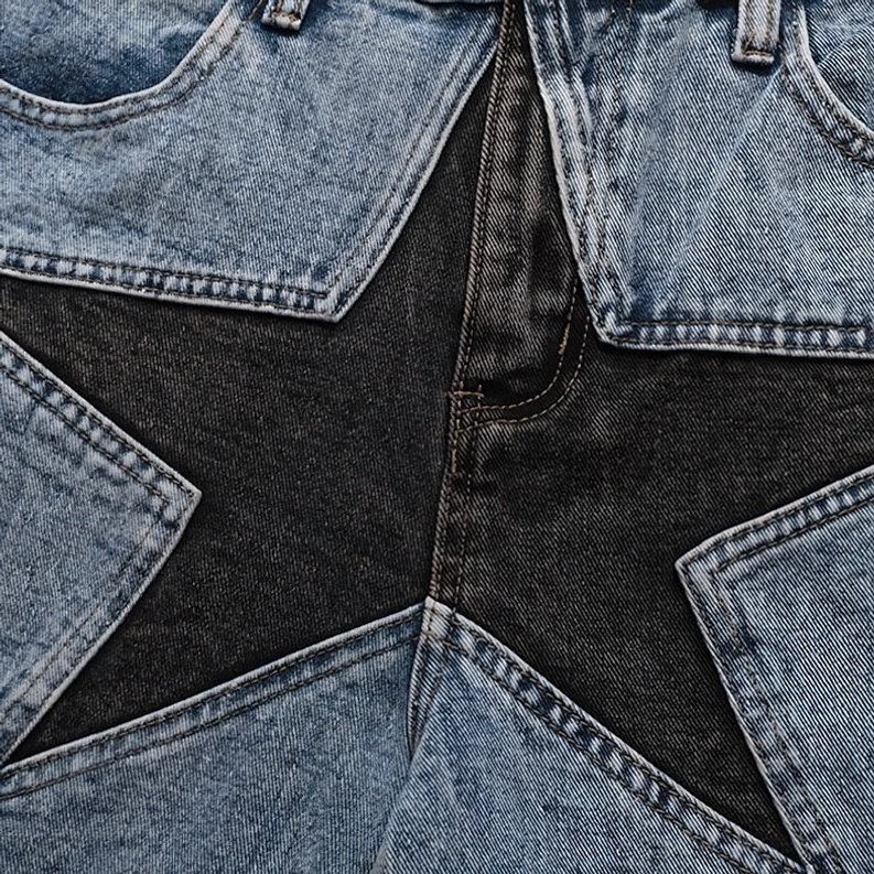 Detaillierte Nahaufnahme des mehrschichtigen schwarzen und hellblauen Stern-Patchwork-Designs mit Kontrastnähten, handgefertigte Nähkonstruktion auf gothic Shorts
