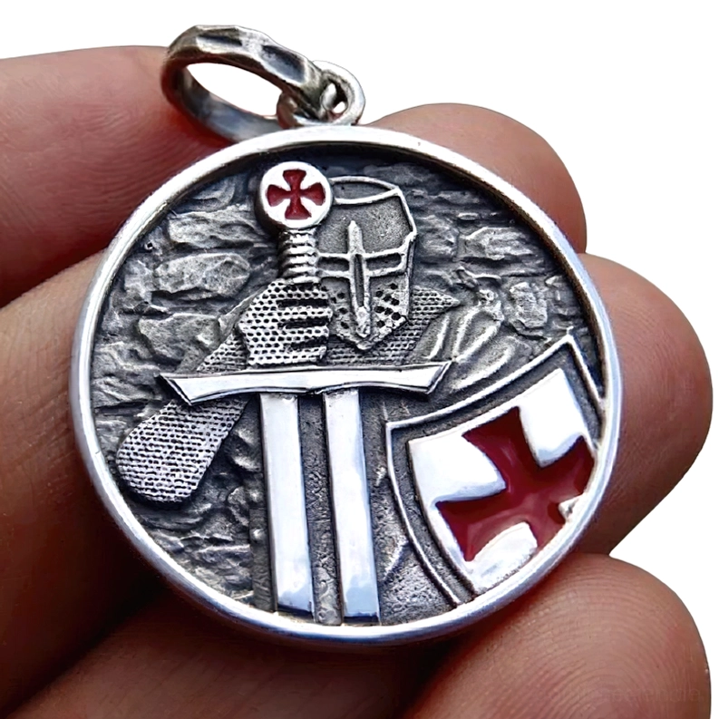Nahaufnahme Templer-Anhänger in der Hand, antikes Silber-Finish mit roten Emaille-Kreuzdetails, schwert-schild-motiv-close-up