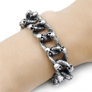 Gotisches Totenkopf-Kettenarmband am Handgelenk getragen Nahaufnahme Seite zeigt verwittertes Vintage-Silberfinish schwere Kettenkonstruktion und strukturell integrierte Schädel