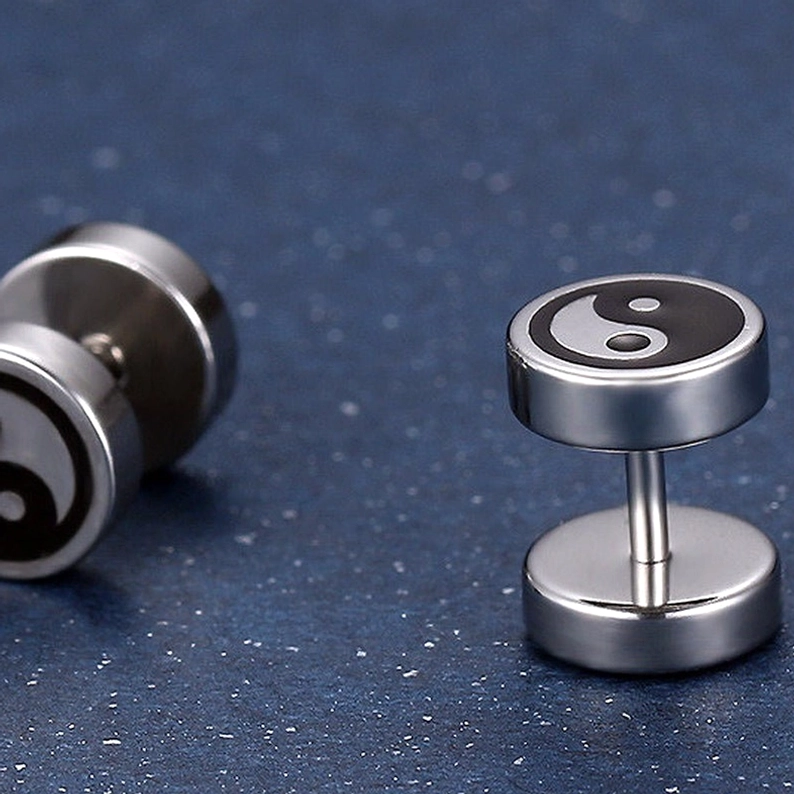 Yin Yang Stecker-Ohrringe aus mehreren Winkeln, hantelförmiger chirurgischer Edelstahl mit Tai Chi Symbol, funkelnder dunkeltürkiser Hintergrund, zeigt 360-Grad-Perspektive des Designs